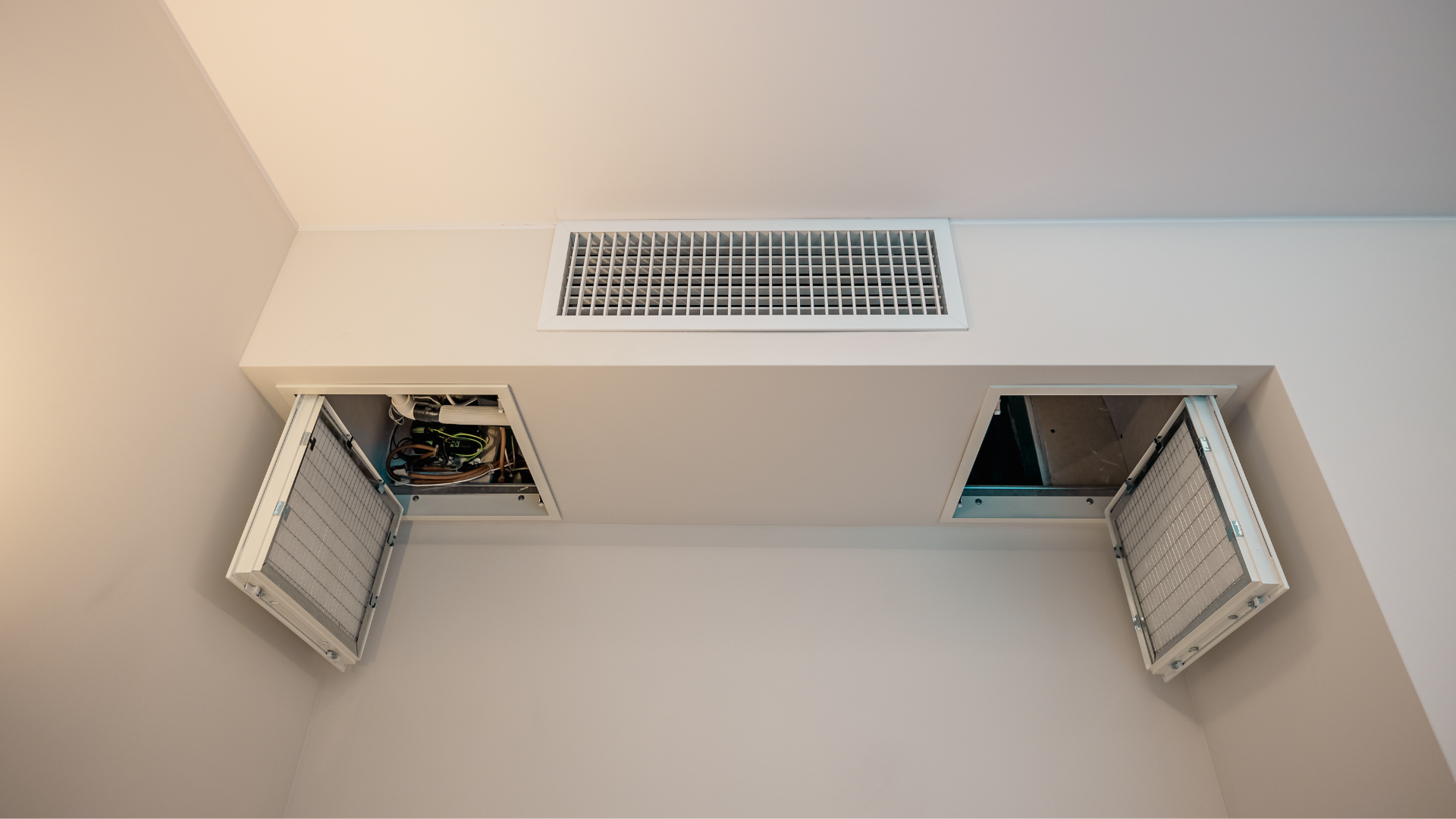 Invisible technology: air filtration and VMC maintenance Ceiling detail of a Controlled Mechanical Ventilation (VMC) vent with open inspection hatches and noise-reducing filters for trapping pollen and dust.