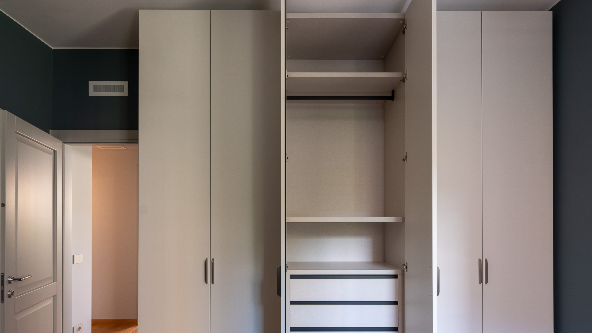 Armadiatura a muro su misura con vani interni a vista, all'interno di una stanza protetta da muffa e umidità eccessiva grazie al controllo igrometrico del sistema di ventilazione.