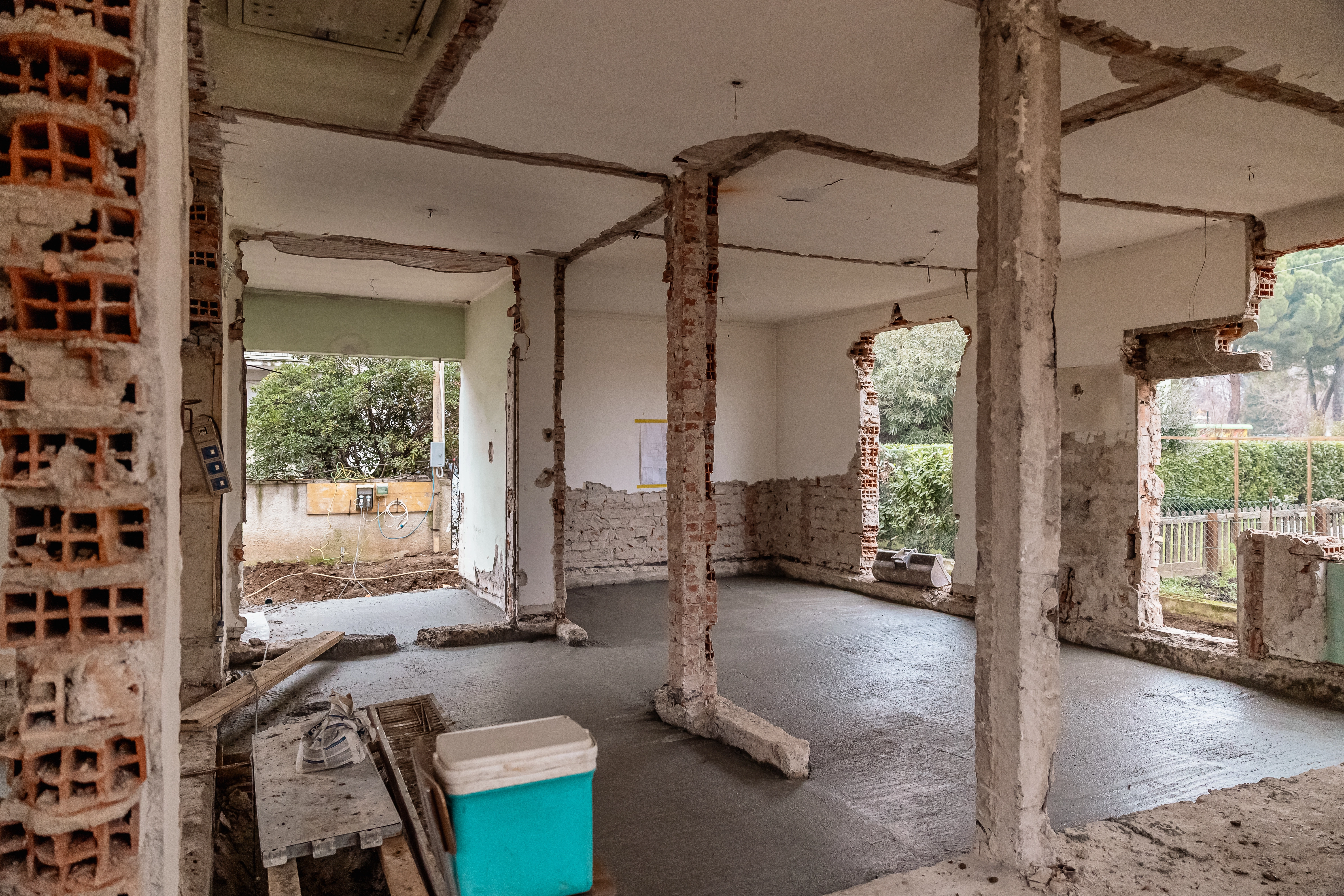 Fase di cantiere di una ristrutturazione edilizia profonda, con pilastri strutturali ed elementi portanti in mattoni e cemento a vista prima delle finiture.
