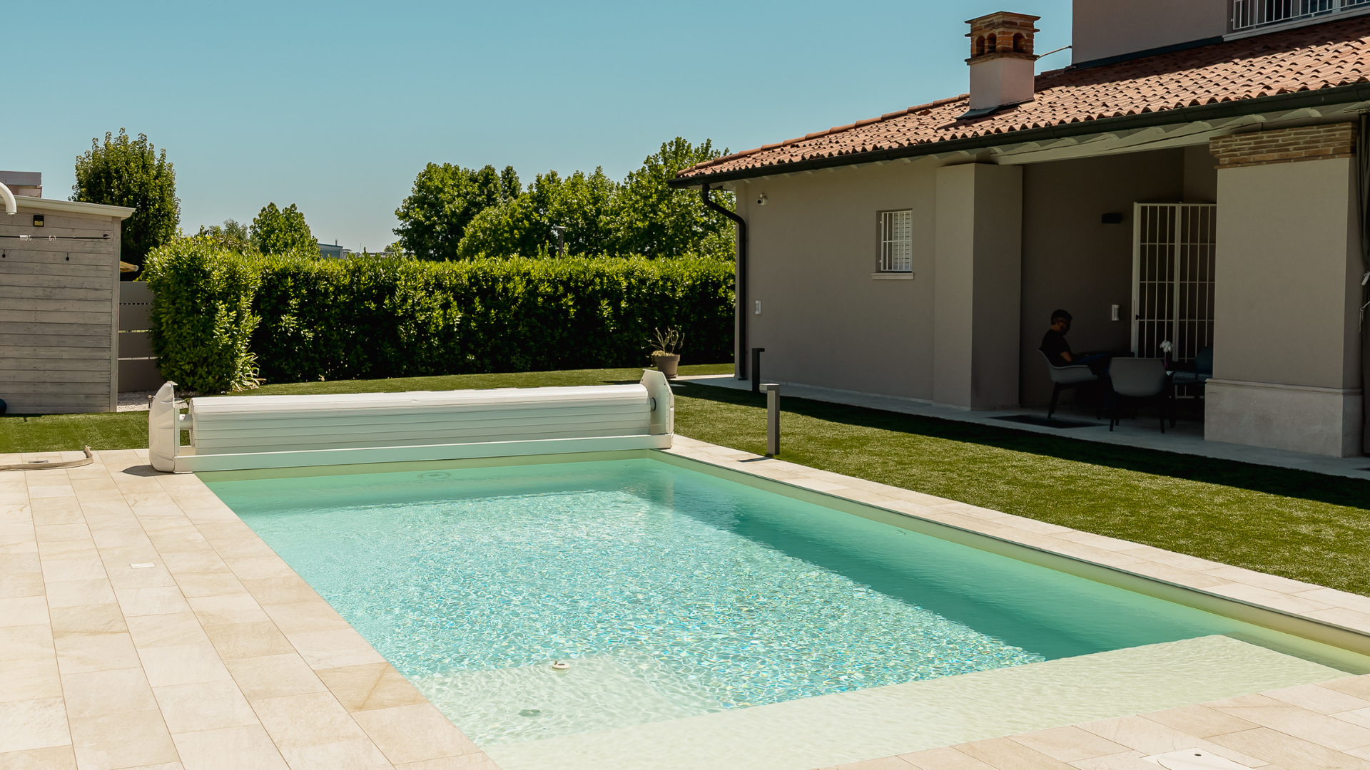 Primo piano del riflesso dell'acqua cristallina all'interno di una piscina con bordo in lastre di pietra chiara.