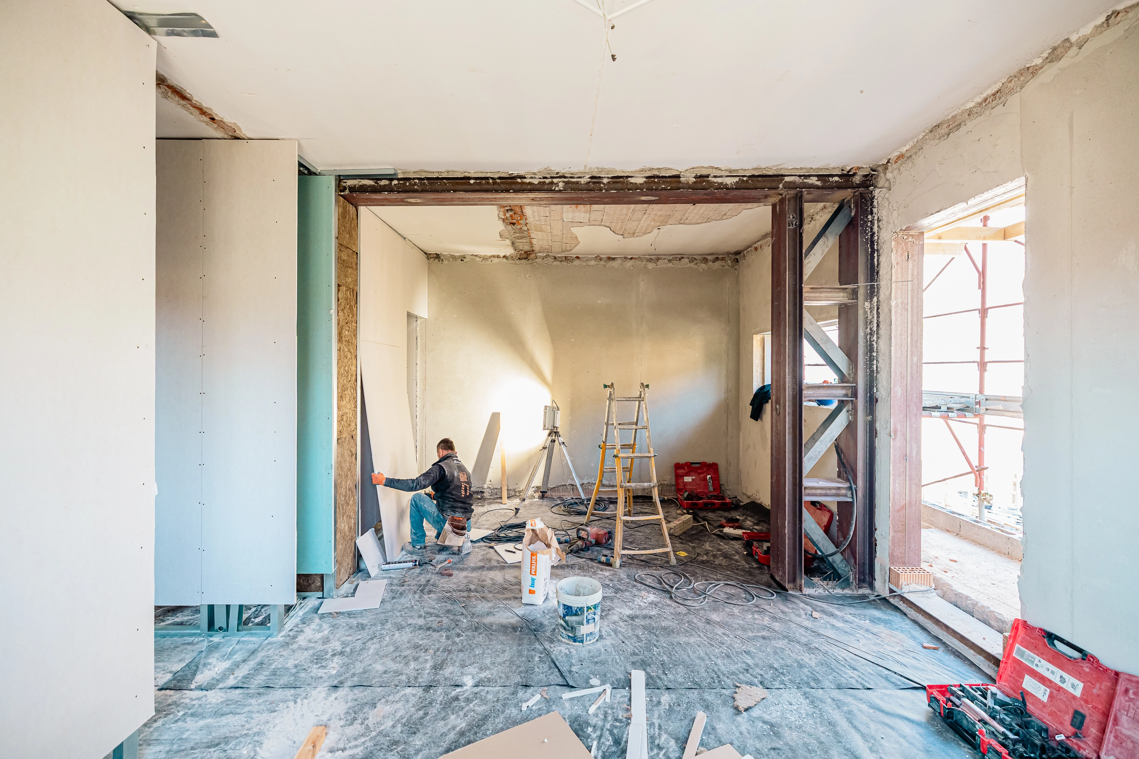 Artigiano specializzato al lavoro all'interno di un cantiere durante la posa di pareti divisorie in cartongesso e isolamento termoacustico.